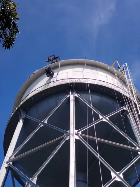 Técnicos pintando un tanque de agua elevado con trabajo en altura